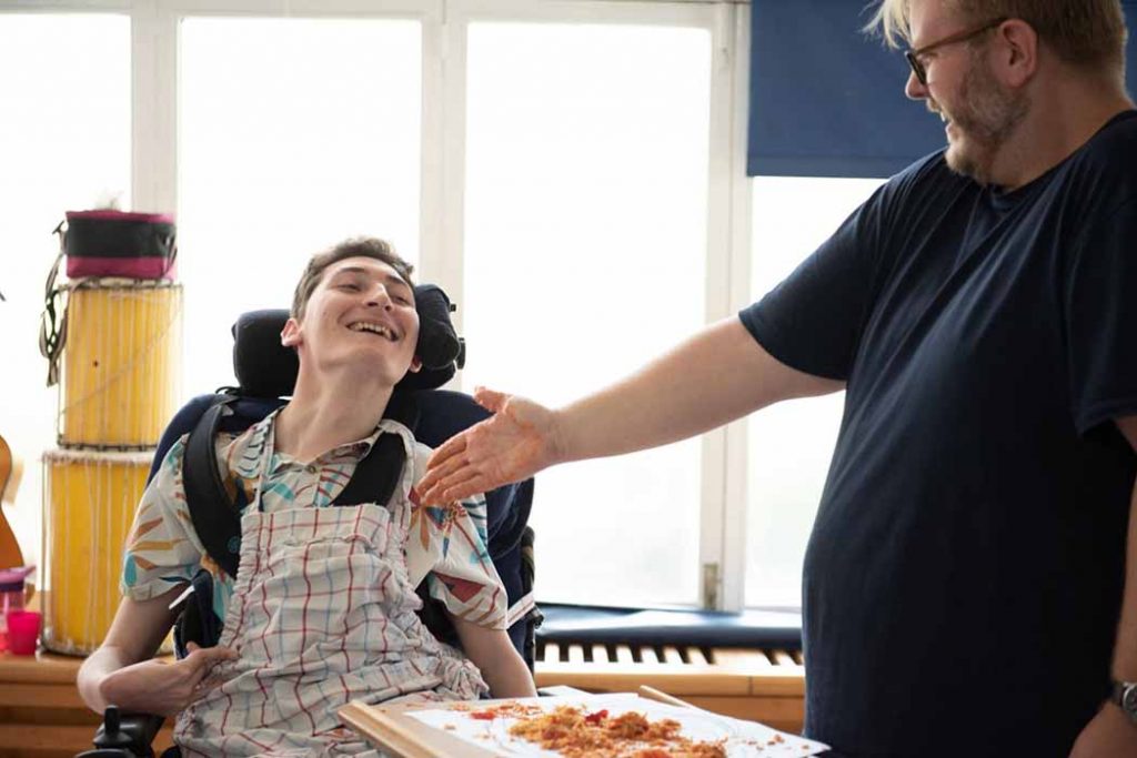 a disabled man and carer share a laugh together